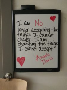 Image of a white board that reads "I am no longer accepting the things I cannot change. I am changing the things I cannot accept. Angela Davis"